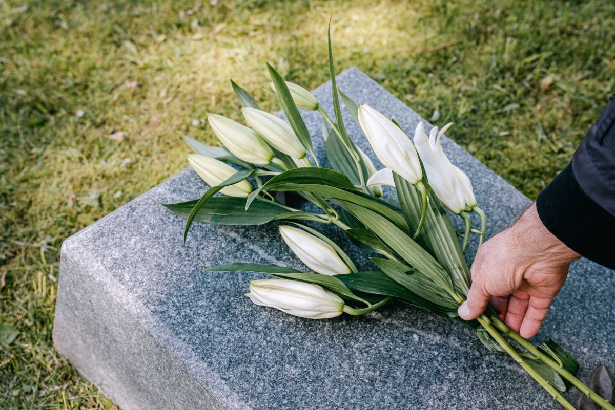 Mains déposant des fleurs sur une sépulture entretenue avec soin